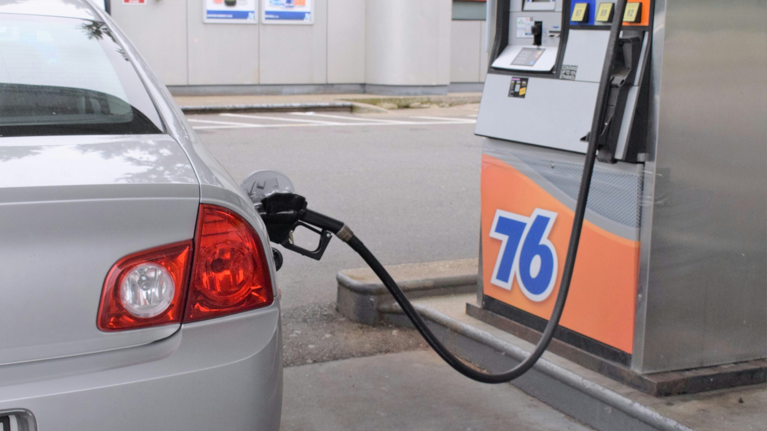 An image of a petrol pump connected to a car's fuel tank.